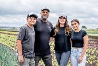 Shane Singh and his wife Jennifer, along with their children Nathan and Lauren, pause for a moment in their field of leeks and lettuce near Bradford, Ontario. Photo by Paul Novosad. 