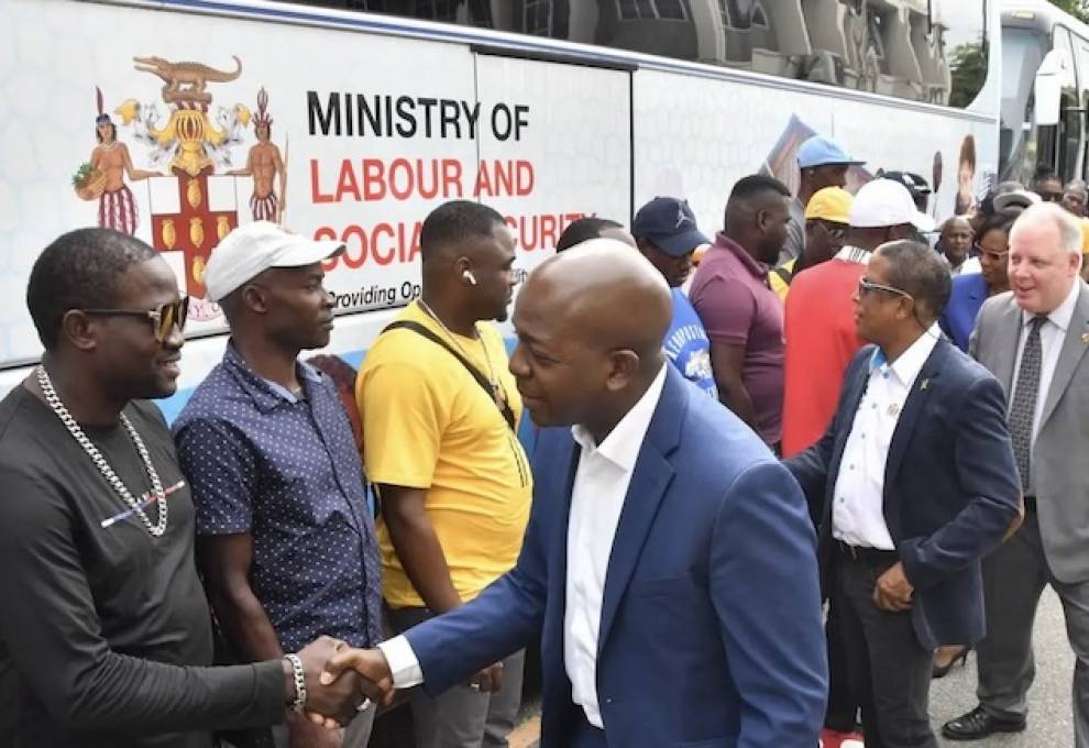 Pearnel Charles Jr (right, foreground), Jamaica minister of labour and social security, along with Norman Dunn (second right, foreground), former minister of state, Ministry of Labour and Social Security; and Michael Lazaruk, senior trade commissioner, Canadian High Commission, extend wishes for safe travel to farm workers before they departed for Canada on February 7. Photo by Naphtali Junior. 